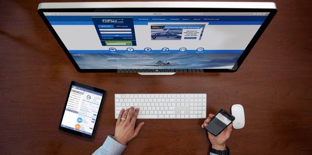 Desk with computer, iPad and iPhone displaying FltPlan services