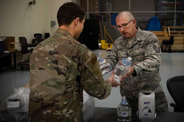 Senior Master Sgt. Michael Welch, 50th Contracting Squadron superintendent, distributes sanitizer to an Airman at the 50th Logistics Readiness Flight warehouse at Schriever Air Force Base, Colorado, April 2, 2020. The 50th CONS secured sanitizing supplies to units across the base to prevent Airmen from contracting COVID-19. (Photo: U.S. Air Force / Airman 1st Class Jonathan Whitely)