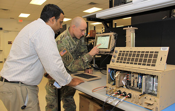 Andradige Silva, electronics engineer for the C5ISR Center's Intelligence and Information Warfare Directorate, and Maj. Doug Williams, assistant product manager for the Joint Battle Command-Platform, access the C4ISR/Electronic Warfare Modular Open Suite of Standards (CMOSS). (Photo: U.S. Army)