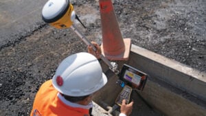 A construction worker at Lima’s airport uses a Trimble GNSS receiver and a TSC7 controller. Requirements included precisely positioning the bolts for more than 700 seismic isolators. (Photo: Trimble)