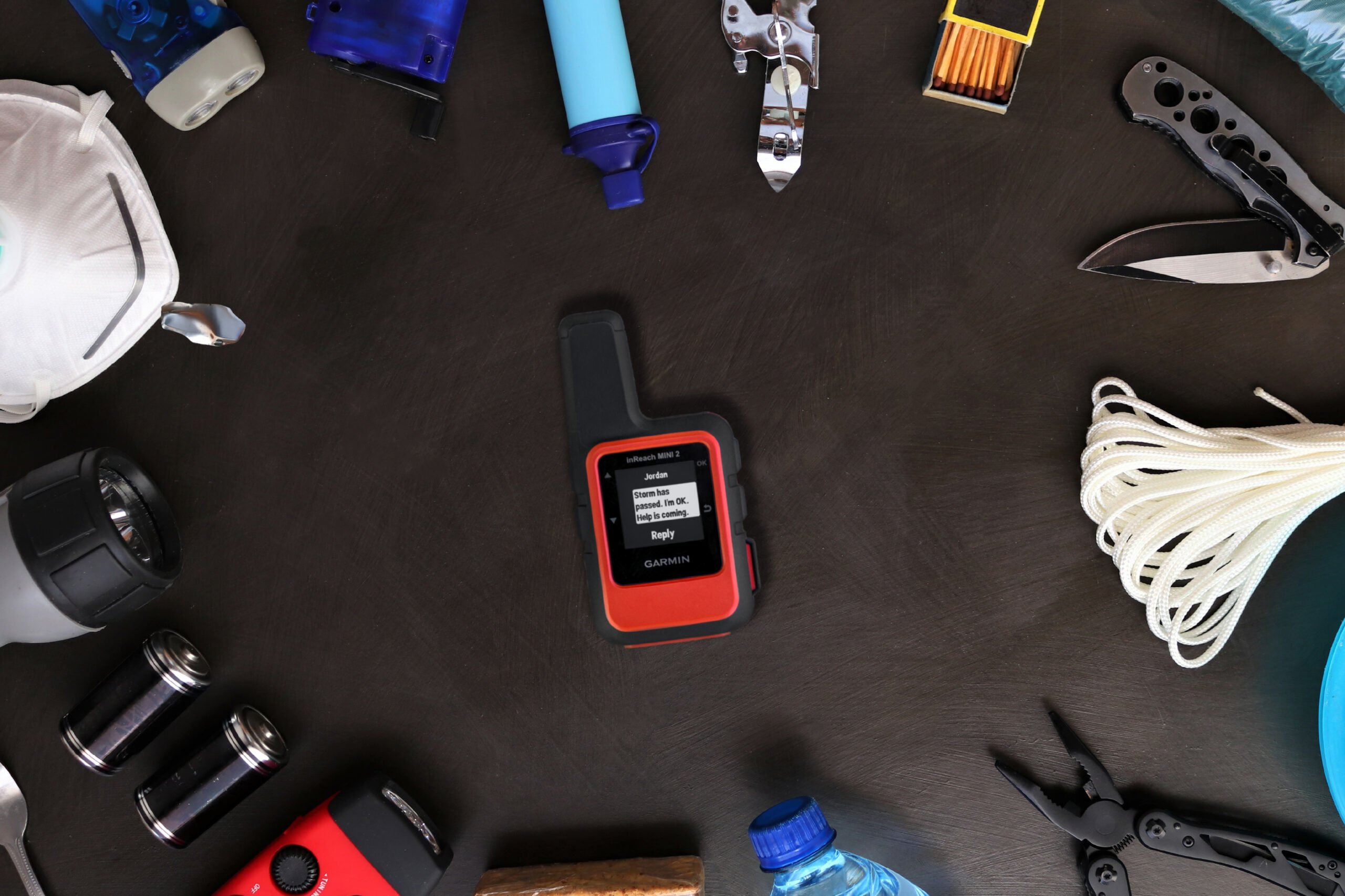 A Garmin inReach Mini 2 satellite communicator is surrounded by disaster preparation essentials.