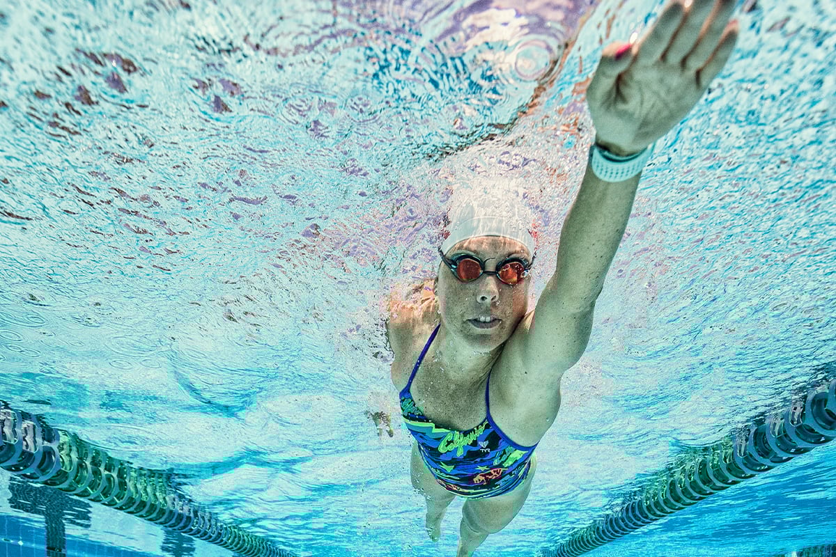 A woman wearing a Garmin swimming smartwatch swims in a pool.