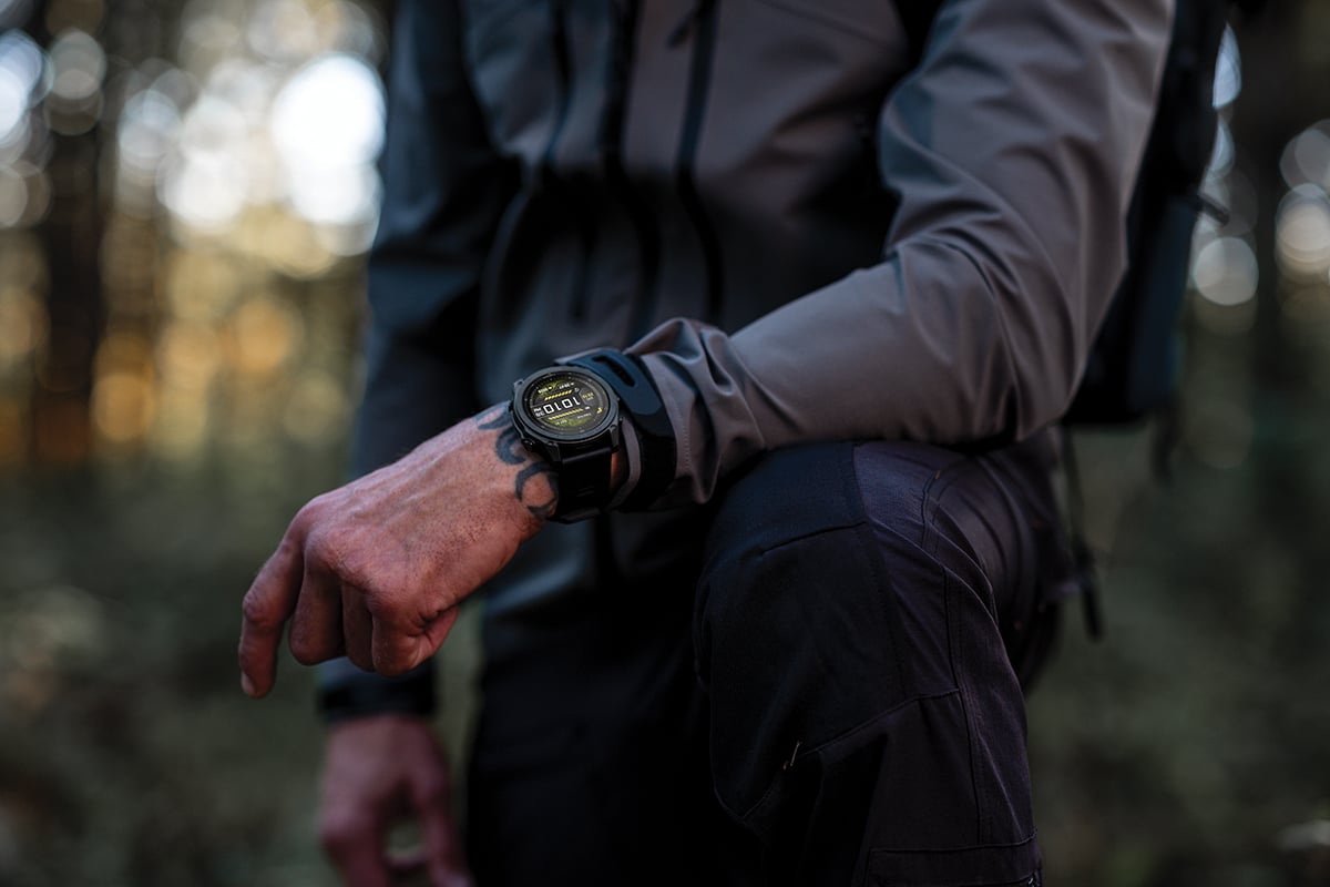 A man wearing a Garmin tactix 8 smartwatch rests his wrist on his knee.