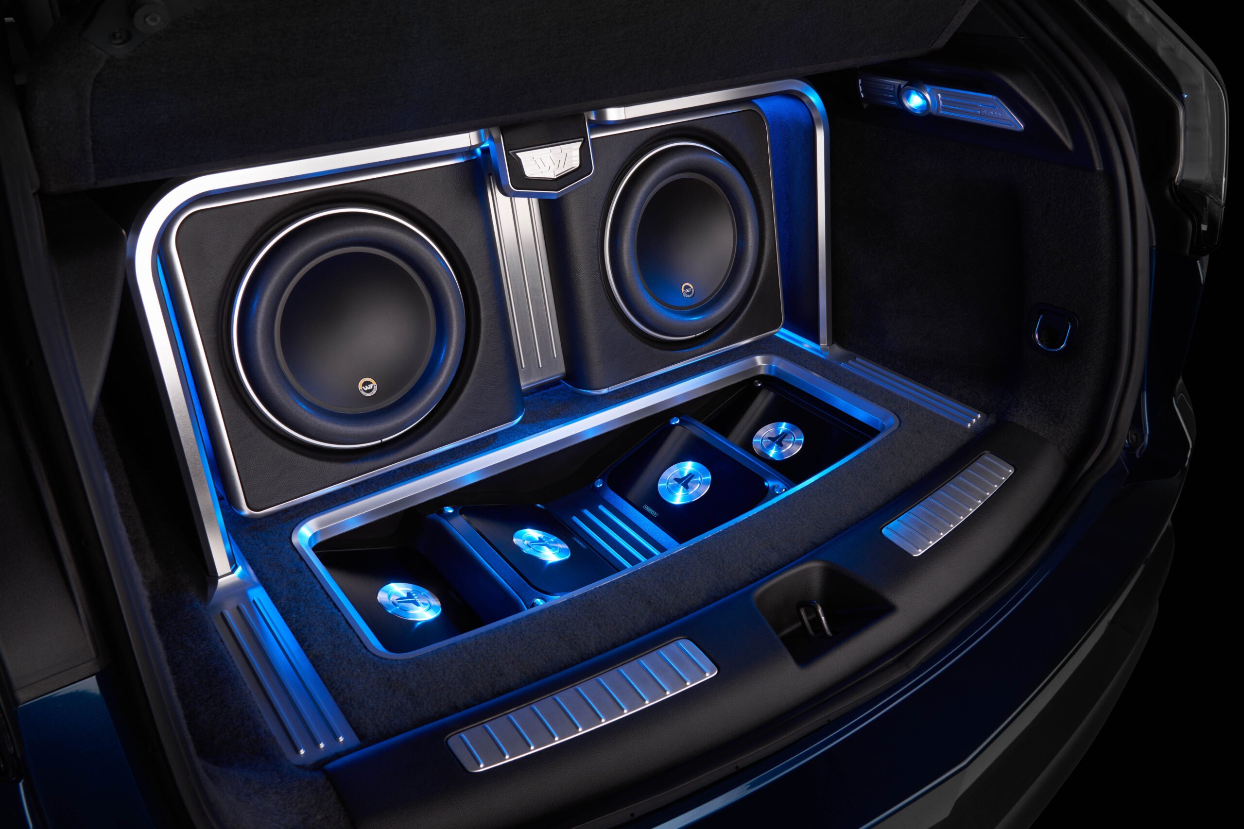 JL Audio products in a trunk and lit up by blue LEDs.