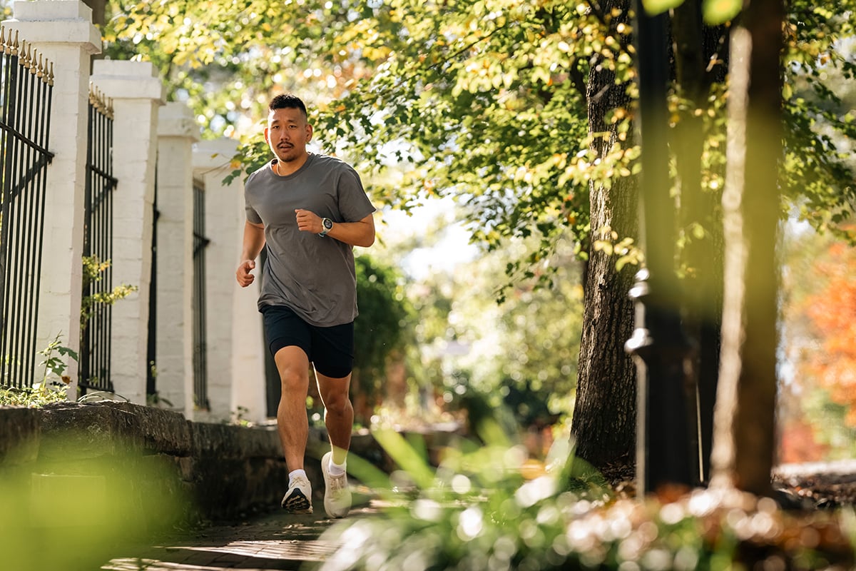 A man wearing a Garmin Forerunner running smartwatch runs down a path.