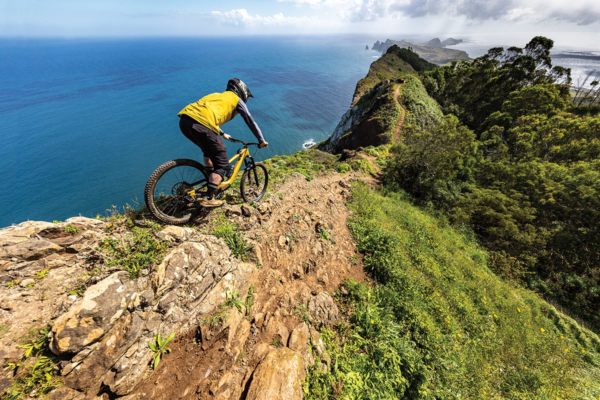 A mountain biker using Edge MTB rides along a trail near a coast.