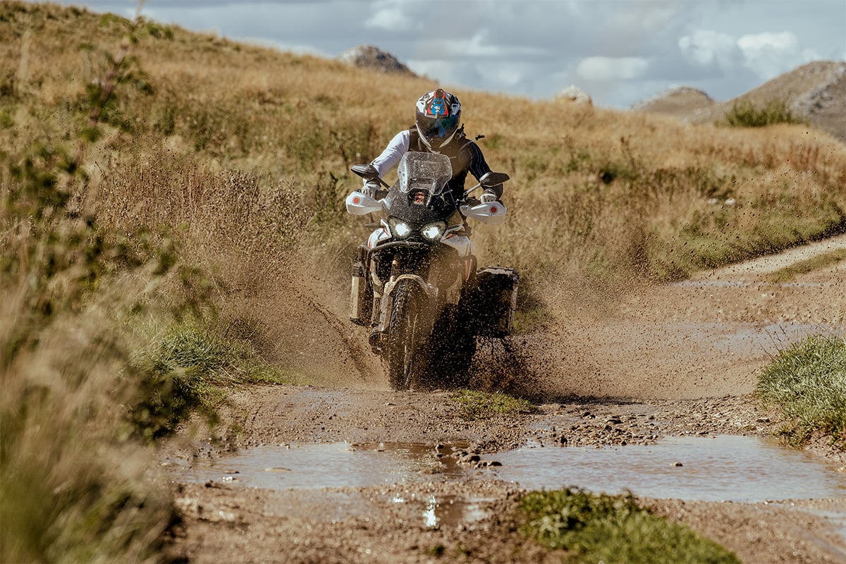 A person on a motorcycle and using a Garmin off-road GPS navigator rides through dirt.