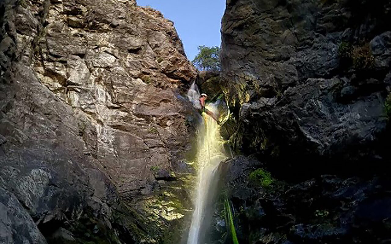 Michelle rappelling down a waterfall while shining the flashlight from her fēnix 7X Pro smartwatch.