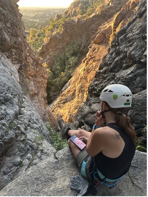 Michelle sitting atop the edge of a cliff. 