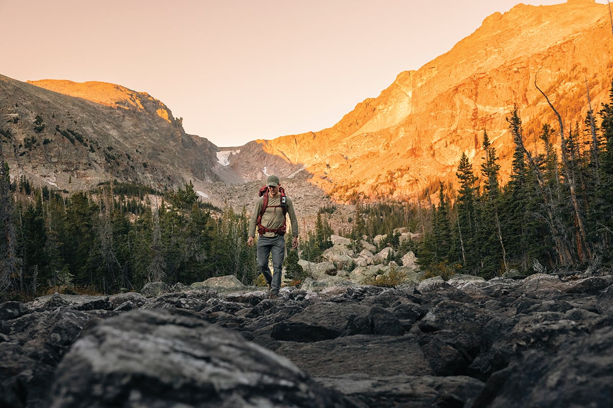 A backpacker hikes with the Garmin GPSMAP H1 Plus handheld.