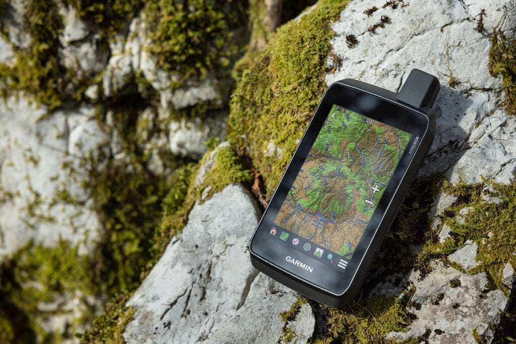 The Montana 710 handheld GPS navigator lays on a mossy rock.