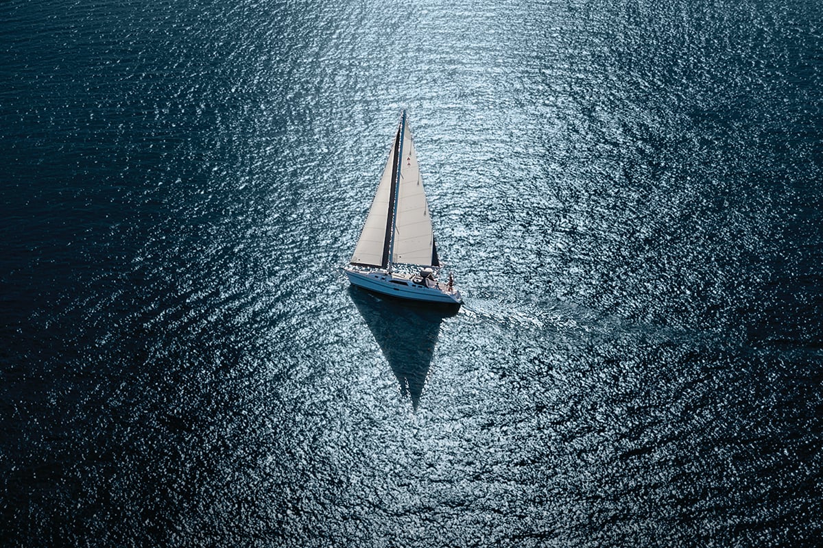 Overhead image of a sailboat on coastal waters.