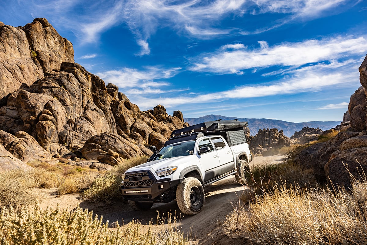 An overlanding rig equipped with the Garmin Tread 2 GPS navigator treks over a dirt road.