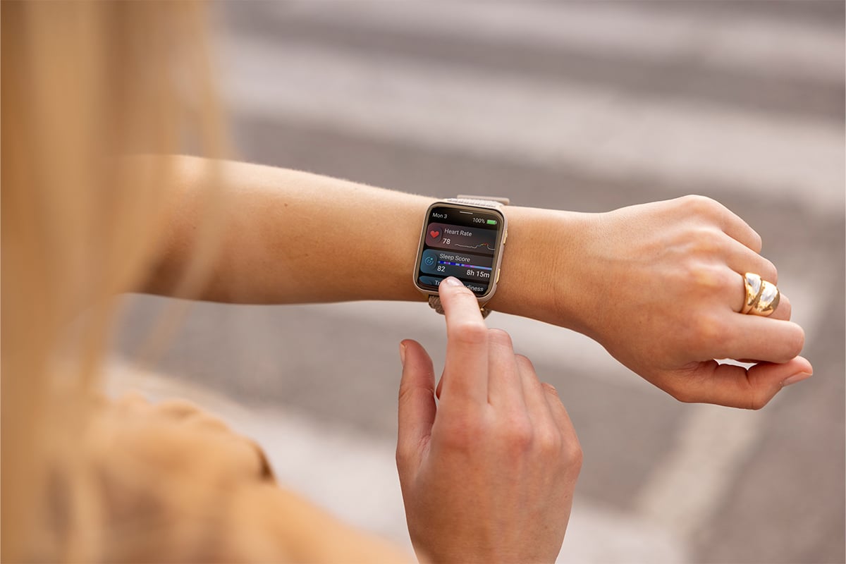 A woman wearing the Garmin Venu X1 smartwatch checks her heart rate and sleep score.