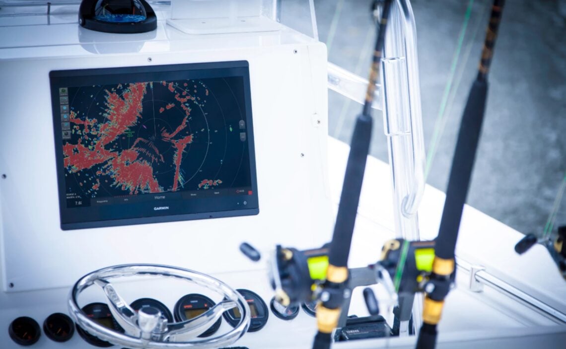 A radar display on a boat with fishing poles in the front.