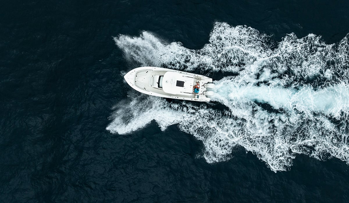 Overhead view of a boat sailing on the ocean with waves on either side.