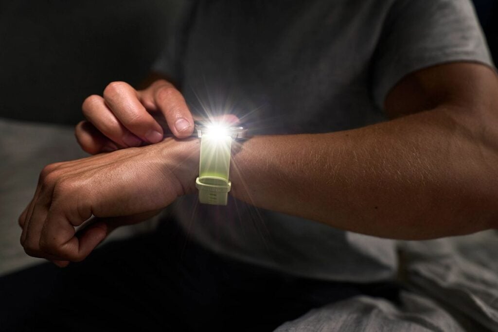 A man turns on the built-in LED flashlight on the Garmin Venu 4 smartwatch.