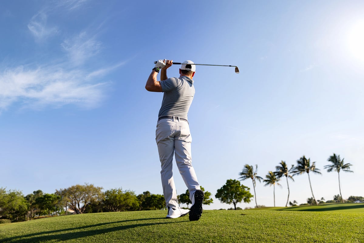 A man wearing the Garmin Approach S70 GPS smartwatch golfs.