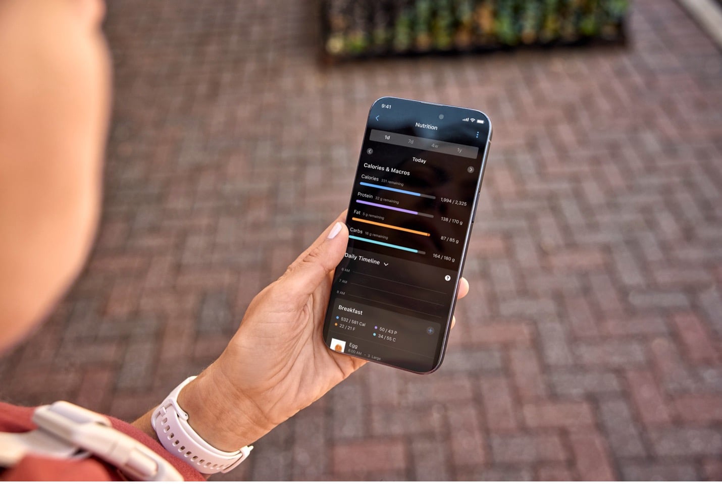 Garmin user looking at their phone with nutrition details being depicted on the screen.