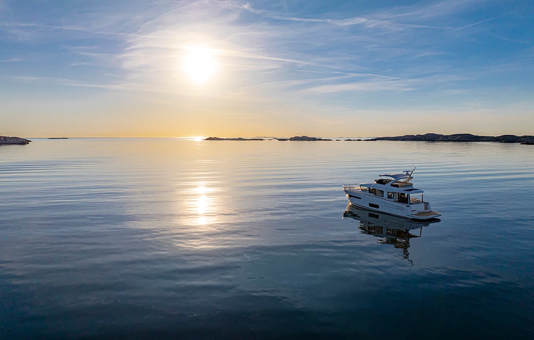 A boat on calm waters looking towards the sun.