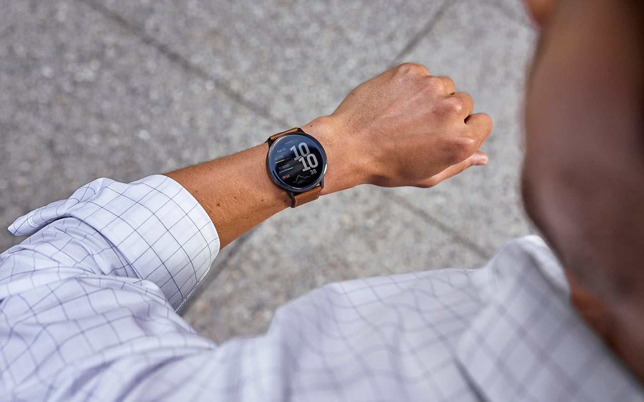 Someone in a dress shirt looking at the Garmin watch on their wrist.