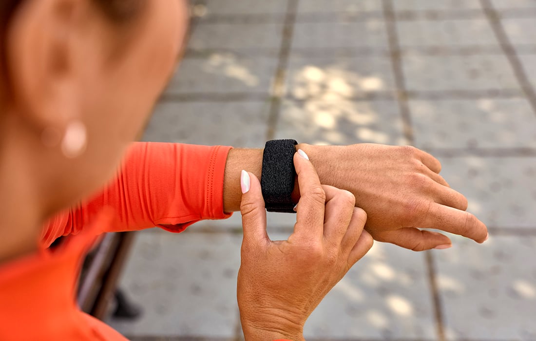 Someone pressing the button on the side of their CIRQA Smart Band before starting an activity. The band is being worn on the wrist.