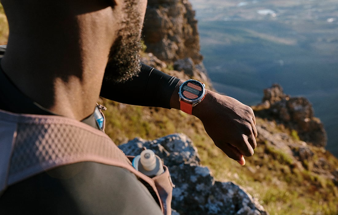 A man at the edge of cliff looking down at the fēnix 9 smartwatch on his wrist.